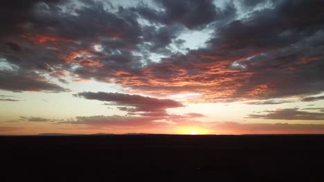 Toma-Aérea-De-Unas-Espectaculares-Nubes-Anaranjadas-Al-Atardecer-Con-El-Horizonte-En-La-Toma