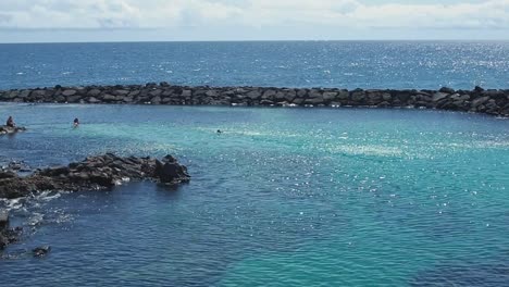 People-swimming-in-a-beautiful-calm-blue-sea-during-summer-time