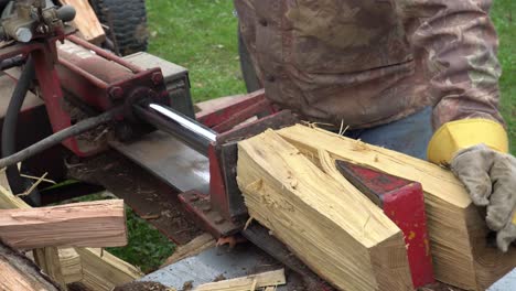 A-man-using-a-hydraulic-log-splitter-to-make-firewood-for-the-winter