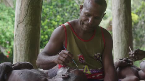 Medium-shot,-man-face-painting-another-man,-inside-the-hut