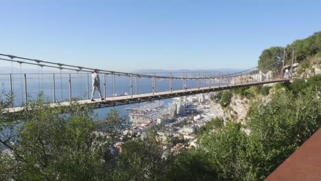 Weite-Aufnahme-Eines-Mannes,-Der-Eine-Brücke-überquert,-Mit-Atemberaubender-Aussicht-Auf-Gibraltar