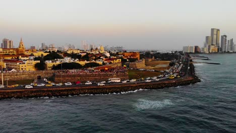 Aerial,-pan,-drone-shot-of-rush-hour-traffic-on-the-Avenida-Santader-road,-the-Cartagena-skyline-in-the-background,-during-dusk,-in-Colombia