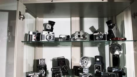 Dolly-out-of-a-glass-cabinet-filled-with-old-vintage-cameras