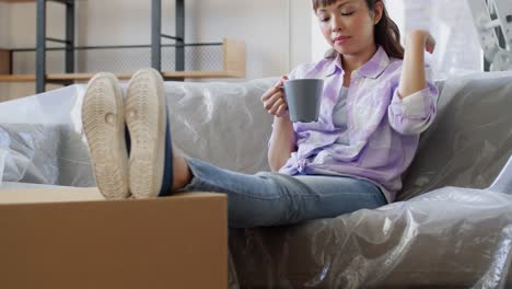 Women-Moving-to-New-Home-and-Drinking-Coffee.people,-repair-and-real-estate-concept--smiling-women-with-stuff-moving-to-new-home,-drinking-coffee-or-tea-and-talking