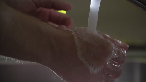 Prevention-coronavirus-Close-Up-of-man-washing-his-hands-with-running-water-and-green-soap-in-sink