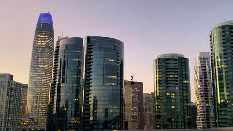 Downtown-office-buildings-view-in-motion-at-sunset-from-afar,-highway---ground-level