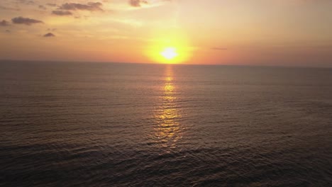 Aerial-drone-view-of-the-sunset-at-the-beach-in-Canggu,-Bali-Indonesia,-flying-backwards