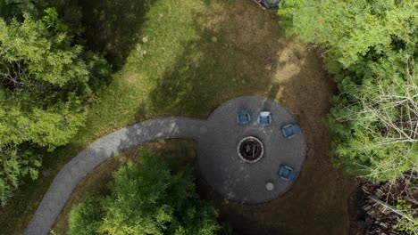 An-amazing-top-down-drone-shot-pulling-away-and-rotating-as-it-gets-higher-and-higher-above-the-beautiful-yard,-with-a-stone-pathway-leading-up-to-a-fire-pit