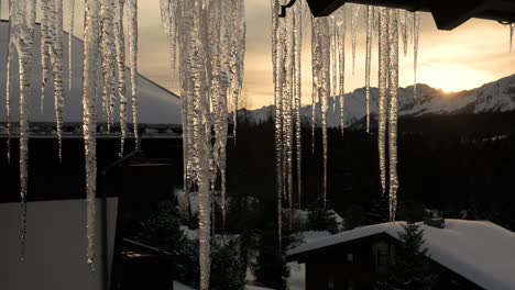 Schmelzende-Eiszapfen-Bei-Sonnenaufgang-Vor-Der-Kulisse-Schneebedeckter-Berge-Und-Wälder