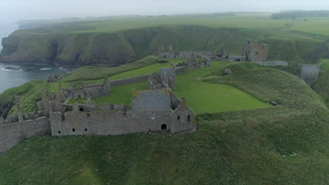 Una-Vista-Aérea-Del-Castillo-De-Dunnottar-En-Un-Día-Brumoso-Y-Nublado