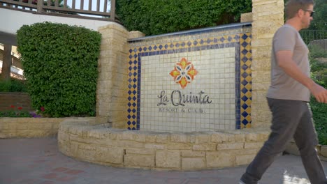 Static-shot-of-a-man-passing-the-La-Quinta-resort-and-club-sign,-in-Los-Angeles,-California,-USA