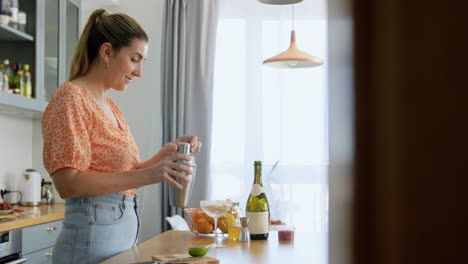 Frau-Mit-Shaker-Gießt-Cocktail-Ins-Glas.-Getränke-Und-Personen-Konzept.-Junge-Frau-Mit-Shaker-Gießt-Cocktail-Ins-Glas-In-Der-Küche-Zu-Hause