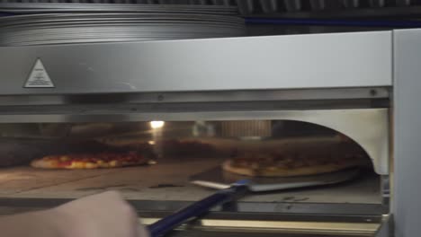 Pizza-chef-checks-on-a-pizza-before-removing-it-from-the-oven