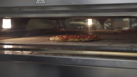 A-pizza-chef-checks-the-pizza-and-removes-it-from-the-oven