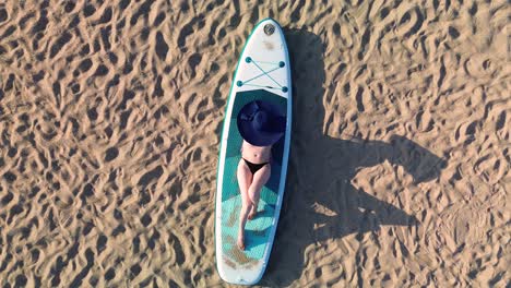 Frau-Liegt-Mit-Hut-Auf-Surfbrett