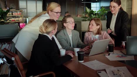 Confident-group-Business-Woman-in-business-clothes-sitting-at-a-table-in-the-office-in-front-of-a-laptop-and-communicating-about-solving-their-problem-and-current-ideas-about-work-In-the-office