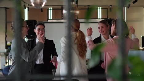 Side-view-of-a-group-of-happy-businesswomen-in-business-clothes-dancing-while-celebrating-their-Victory-and-success-while-working-in-a-modern-office