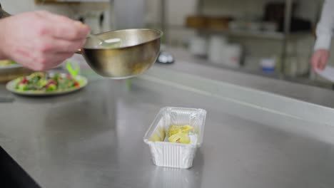 A-professional-male-chef-pours-sauce-over-the-finished-dish-before-delivery-in-a-special-package-for-delivery-from-a-restaurant.-Preparing-food-before-delivery-outside-the-restaurant