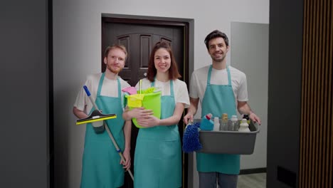 Portrait-of-a-trio-of-professional-cleaners-in-a-blue-apron-with-various-cleaning-items-cleaner-and-mop-in-a-modern-apartment-cleaning-on-call