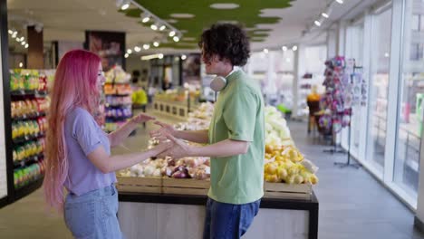 Un-Chico-Moreno-Feliz-Con-Su-Novia-De-Cabello-Rosa-Bailando-Y-Tomados-De-La-Mano-En-Una-Tienda-De-Comestibles