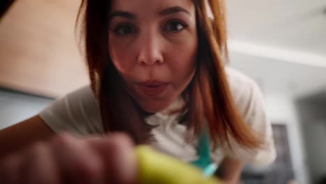 Portrait-of-a-happy-and-cheerful-brunette-cleaning-lady-girl-in-a-white-T-shirt-holding-a-window-and-looking-out-of-it-while-cleaning-in-a-modern-kitchen