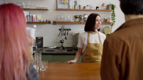 Over-the-shoulder-of-those-waiters-a-brunette-girl-and-a-blond-guy-are-busy-issuing-orders-at-the-cash-register-in-a-cafe-for-a-couple-of-clients