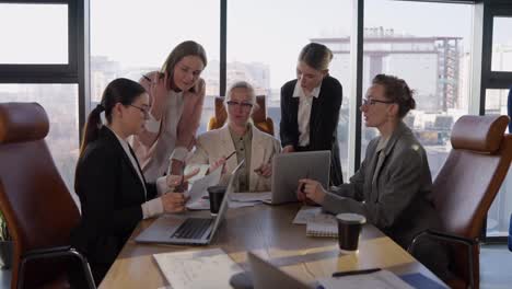 Side-view-of-a-confident-middle-aged-blonde-girl-in-a-white-business-suit-communicates-with-her-colleagues-during-a-meeting-and-listens-to-their-suggestions-and-ideas-while-working-in-the-office