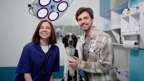 Portrait-of-a-happy-brunette-veterinarian-girl-with-a-veterinary-clinic-visitor-and-his-dog-in-the-veterinarians-office