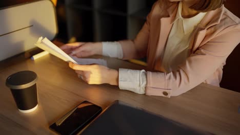 Turn-on-a-confident-middle-aged-blonde-girl-in-a-pink-business-suit-passes-papers-to-her-colleague-and-talks-about-her-plans-and-ideas-while-working-in-the-office-at-the-table