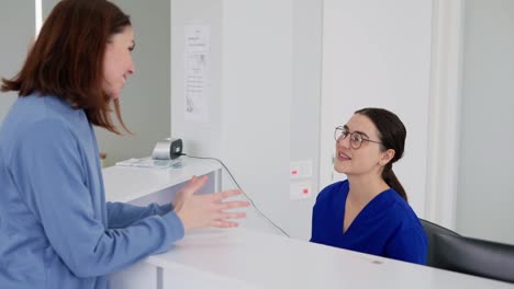 Una-Chica-Morena-Segura-De-Sí-Misma-Con-Gafas-Redondas-Y-Un-Uniforme-Azul,-El-Médico-Se-Encuentra-Con-Un-Paciente-Y-Un-Visitante-En-Una-Clínica-Moderna.-Una-Chica-Morena-Con-Una-Chaqueta-Azul-Durante-Un-Día-De-Trabajo-En-Una-Clínica-Moderna.