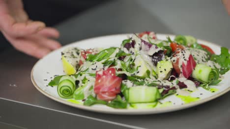 De-Cerca,-Un-Chef-Profesional-Presenta-Su-Plato-Y-Lo-Hace-Girar-En-Círculo-Para-Tener-Una-Vista-Completa-De-La-Ensalada-Y-Todos-Sus-Detalles-En-La-Mesa-En-La-Cocina-De-Un-Restaurante.