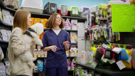 A-confident-blonde-girl-in-a-plaid-shirt-talks-with-a-pet-store-assistant-about-the-best-products-that-can-be-bought-for-her-white-dog-in-a-pet-store