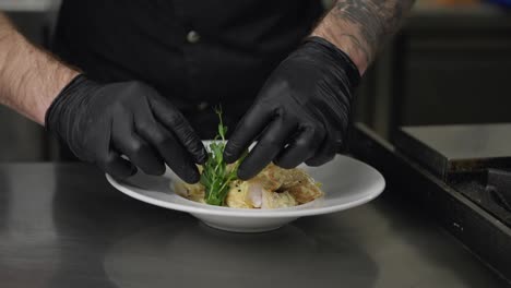 Close-up-a-cook-in-black-rubber-gloves-puts-greens-on-ready-made-dishes-and-gives-them-to-the-restaurant-after-complete-preparation-and-presentation