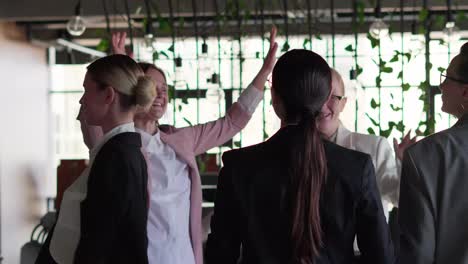 Group-of-happy-businesswomen-in-business-clothes-dancing-during-a-meeting-and-a-short-break-at-work-in-a-modern-office