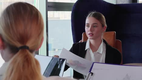 Confident-blonde-businesswoman-girl-in-business-clothes-distributes-to-her-colleagues-the-necessary-schedules-for-an-interview-and-a-general-meeting-to-solve-a-problem-in-a-modern-office