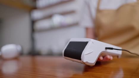 Close-up-a-guy-with-his-hand-brings-the-phone-to-the-terminal-for-online-payment-on-the-counter-in-a-cafe