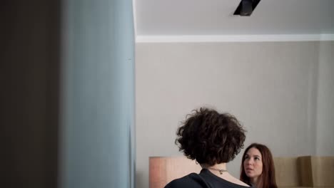 A-brunette-guy-with-curly-hair-arrives-with-a-nail-in-the-wall-and-hangs-a-clock-together-with-a-girl-who-helps-him-at-home