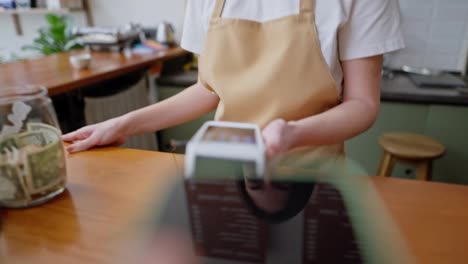 Primer-Plano:-Un-Cliente-Acerca-El-Teléfono-A-La-Terminal-Cuando-Paga-Un-Pedido-De-Una-Camarera-En-El-Mostrador-De-Una-Cafetería.