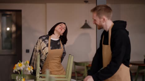 A-happy-brunette-girl-communicates-with-a-guy-waiter-while-they-are-working-together-and-preparing-to-clean-the-cafe-hall