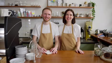 Porträt-Eines-Glücklichen-Brünetten-Kellners-Zusammen-Mit-Seiner-Kollegin,-Einem-Brünetten-Mädchen-An-Der-Kasse-In-Einem-Café