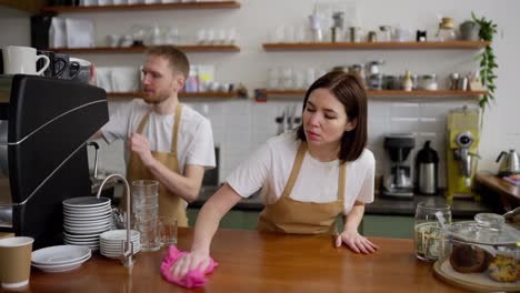 Confident-brunette-girl-cleans-the-counter-while-starting-the-working-day-and-preparing-to-serve-customers-in-a-cafe