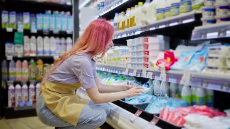 A-girl-with-bright-red-hair-in-an-apron-distributes-goods-at-the-dairy-products-counter-in-a-supermarket