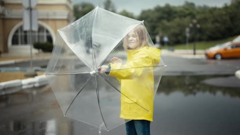 Happy-blonde-teenage-girl-in-a-yellow-jacket-twirls-an-umbrella-in-her-hands-in-the-park-after-the-rain