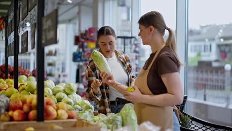 A-brunette-girl-in-a-checkered-shirt-asks-the-Assistant-for-advice-in-a-supermarket-regarding-the-choice-of-vegetables-during-her-shopping