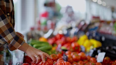 Close-up-a-girl-in-a-checkered-shirt-sorts-out-ripe-vegetables-with-her-hands-on-a-vegetable-counter-in-a-supermarket