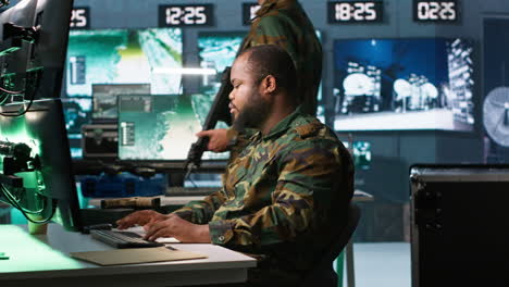 Intelligence-corps-agent-checking-screens,-discussing-with-colleague