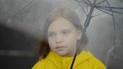 Ein-Trauriges-Blondes-Mädchen-In-Einer-Gelben-Jacke-Hält-Einen-Regenschirm-Und-Sieht-Sich-Beim-Gehen-Bei-Nieselregen-Um