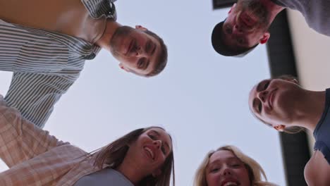 Bottom-view-of-a-happy-group-of-young-friends-looking-down-and-hugging-during-their-party-and-relaxation-in-the-backyard