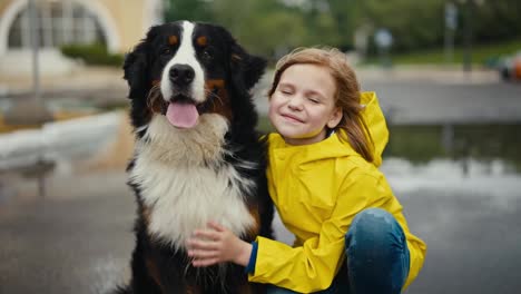 Una-Adolescente-Feliz-Con-Una-Chaqueta-Amarilla-Posando-Con-Su-Gran-Perro-De-Raza-Pura,-Blanco-Y-Negro,-En-El-Parque-Después-De-La-Lluvia-Durante-Una-Caminata