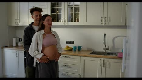 Happy-brunette-pregnant-woman-dancing-with-her-husband-in-the-kitchen-in-the-morning